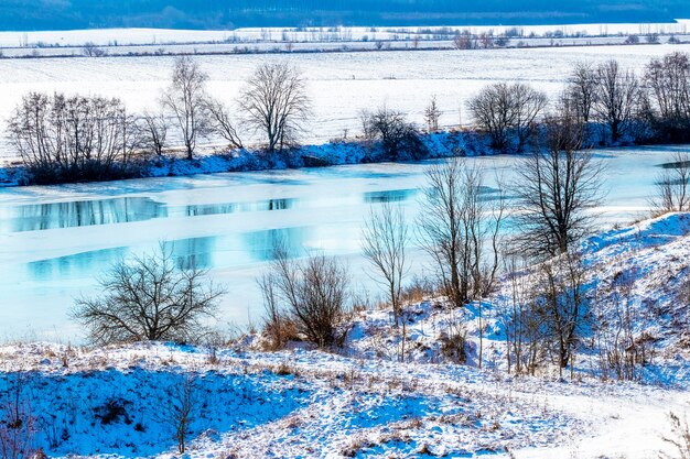 Winterlandschaft mit Fluss und Bäumen am Fluss an einem sonnigen Tag