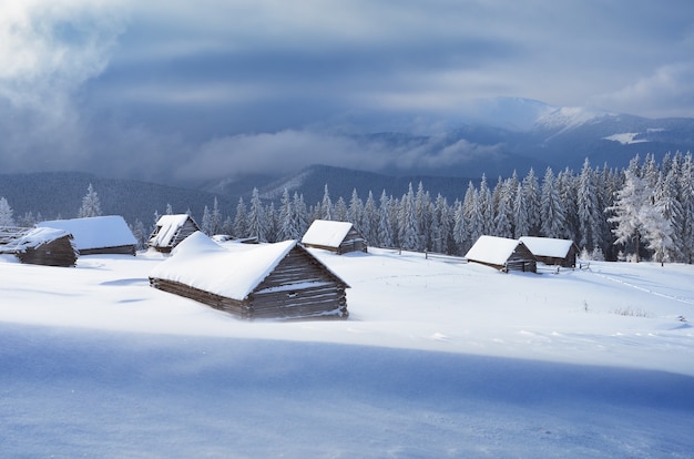 Winterlandschaft mit Holzhäusern in einem Gebirgstal