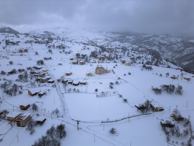 Winterlandschaft mit kleinen Dorfhäusern zwischen schneebedeckten Wäldern in den kalten Bergen Giresun Türkei