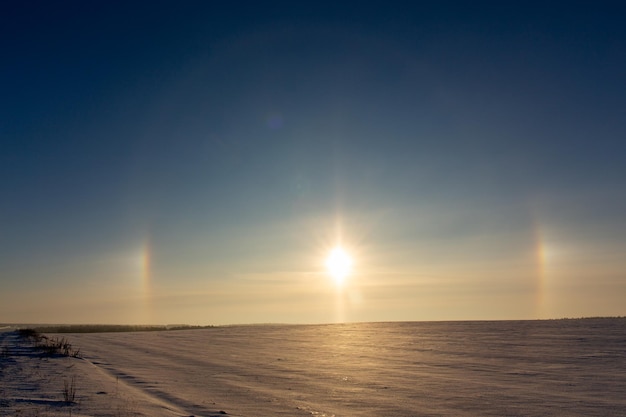 Winterlandschaft mit kreisförmigen Halo-Phänomenen um die Sonne