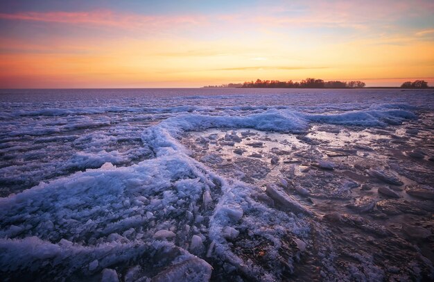 Winterlandschaft mit See und feurigem Himmel des Sonnenuntergangs. Zusammensetzung der Natur.