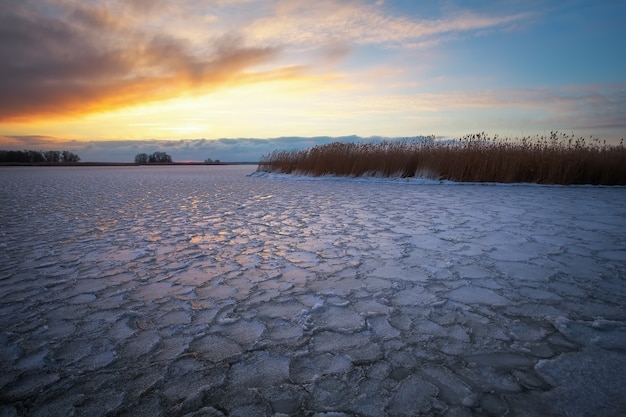 Winterlandschaft mit zugefrorenem See und Sonnenuntergangshimmel. Zusammensetzung der Natur.