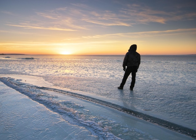 Winterlandschaft und Mann mit Blick auf den Sonnenuntergang