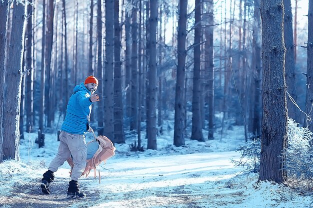 winterlandschaft waldrucksack mann / reisender in moderner winterkleidung im wald, reisen in den bergen europa, schweiz winter