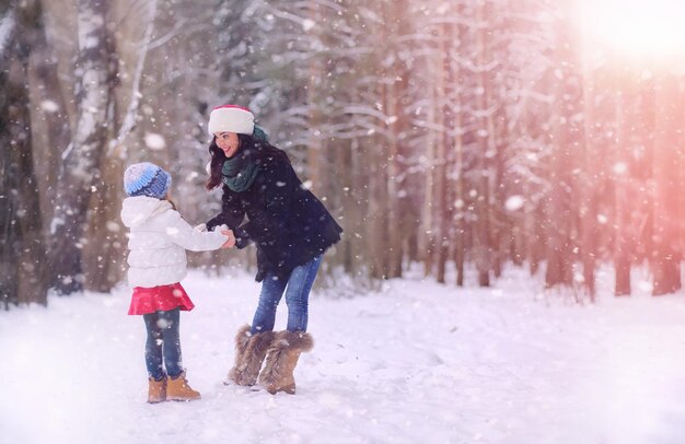 Wintermärchen eine junge Mutter und ihre Tochter fahren mit einem Schlitten im Wald