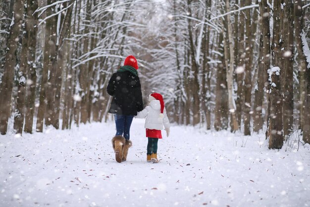 Wintermärchen eine junge Mutter und ihre Tochter fahren mit einem Schlitten im Wald