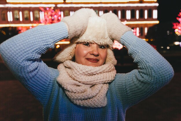 Winternachtporträt einer schönen Frau in Winterkleidung. Pelzmütze und Handschuhe.