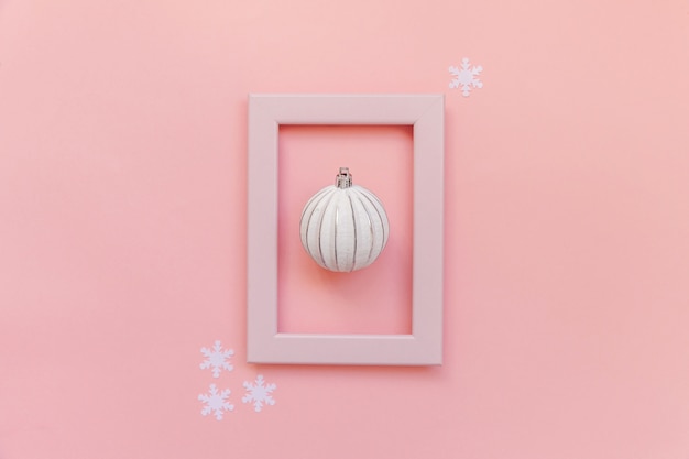 Winterobjekt-Verzierungsball im rosa Rahmen lokalisiert auf rosa Pastellhintergrund