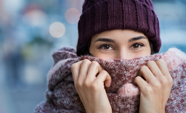 Winterporträt der jungen schönen Frau, die Gesicht mit Wollschal bedeckt