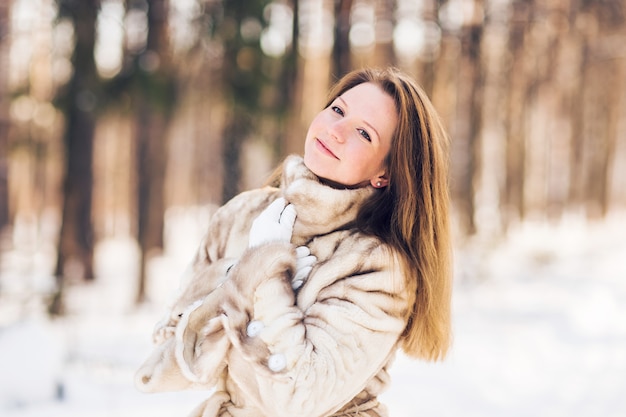 Winterporträt der jungen schönen Frau, die Pelzmantel trägt. Schneewinterschönheitsmodekonzept.