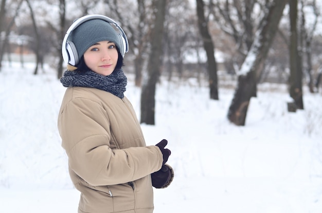 Winterporträt des jungen Mädchens mit Kopfhörern