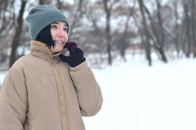 Winterporträt des jungen Mädchens mit Smartphone