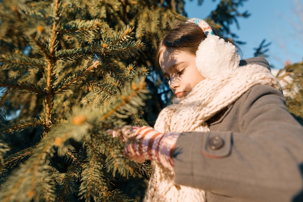 Winterporträt im Freien eines kleinen lächelnden Mädchens in einem gestrickten Schal