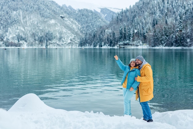 Winterreisen quer durch Europa. Blick auf den Alpensee mit Schnee. Porträt eines erwachsenen Paares verliebter Reisender am Ufer eines Hochgebirgssees.