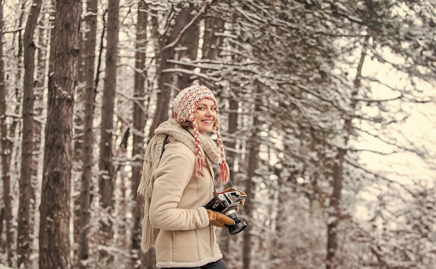 Winterreiseurlaub stilvolle Hipster-Reisende Frau mit Fotokamera im Winterwald Fotograf fotografiert an verschneiten Wintertagen glückliche Frau warme Kleidung Mode