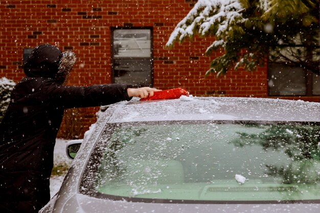 Winterschneesturmfrau entfernen nach Schnee von Windschutzscheibe mit Auto, das Schnee reinigt