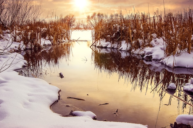 Wintersonnenuntergang am Fluss, Winterlandschaft mit Fluss und Schilf