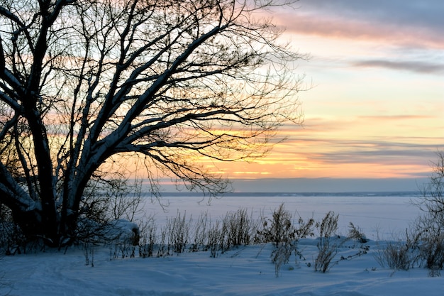 Wintersonnenuntergang auf einem zugefrorenen Fluss