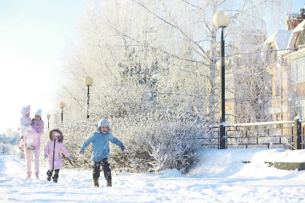 Winterspaziergang auf der Straße an einem sonnigen frostigen Tag Familie mit Kindern spielen Schneebälle im Park Winterferien und Familienurlaub