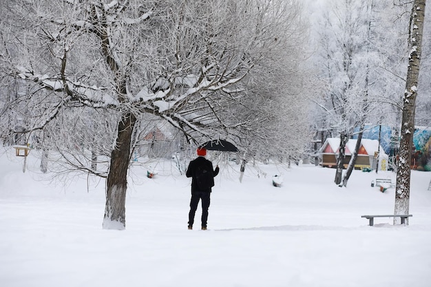 Winterspaziergang mit Regenschirm.Mann in einem Mantel mit Regenschirm, Spaziergang vor dem Hintergrund der Winterlandschaft, Winteransicht