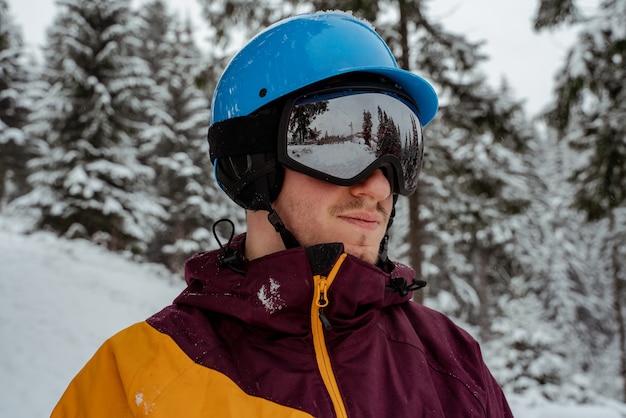 Wintersport und Erholung, Freizeitaktivitäten im Freien. Mann in Skiausrüstung, Schutzbrille tragend. Snowboardermann, der am Berg wandert.