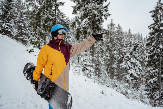 Wintersport und Erholung, Freizeitaktivitäten im Freien. Mann in Skiausrüstung, Schutzbrille tragend. Snowboardermann, der am Berg wandert.