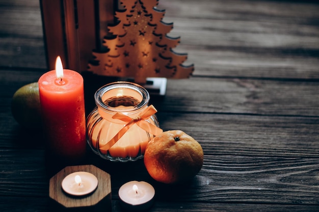 Winterstillleben mit Fellen Orangefarbene Duftkerze in einem figürlichen Leuchter mit Schleife