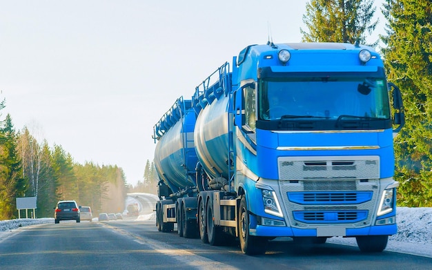 Winterstraße mit Schnee. LKW in Finnland. Lastwagen und kalte Landschaft Lapplands. Europa Wald. Autobahnfahrt durch die finnische Stadt. Fahrbahn und Route schneebedeckter Straßenausflug. Lieferung bei Bergabfahrt