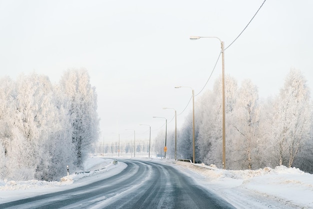 Winterstraße und ein schneebedeckter Wald des kalten Finnlands von Lappland.