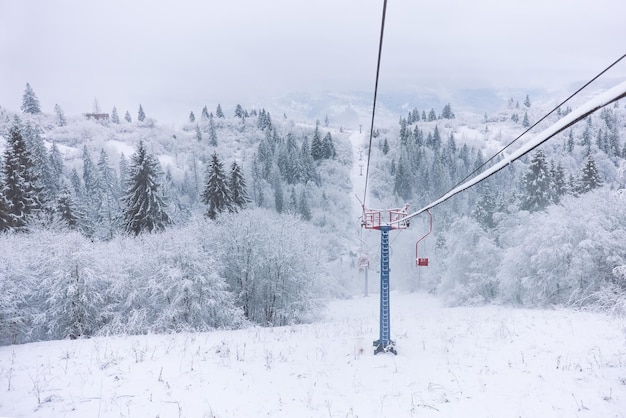 Winterszenenansicht des verschneiten Kiefernwaldes und der Skiseilbahn in den Bergen