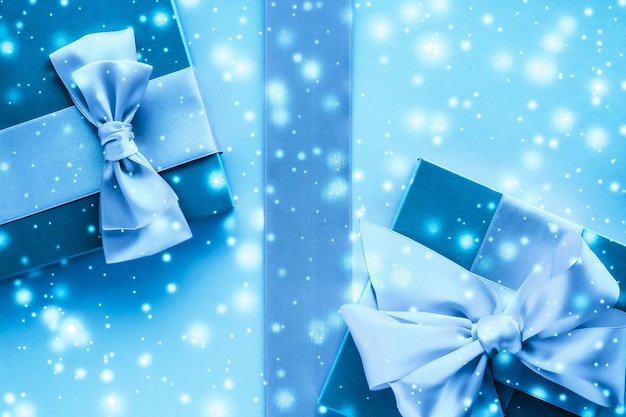 Winterurlaub Geschenke und glühender Schnee auf gefrorenem blauem Hintergrund Weihnachtsgeschenke überraschen