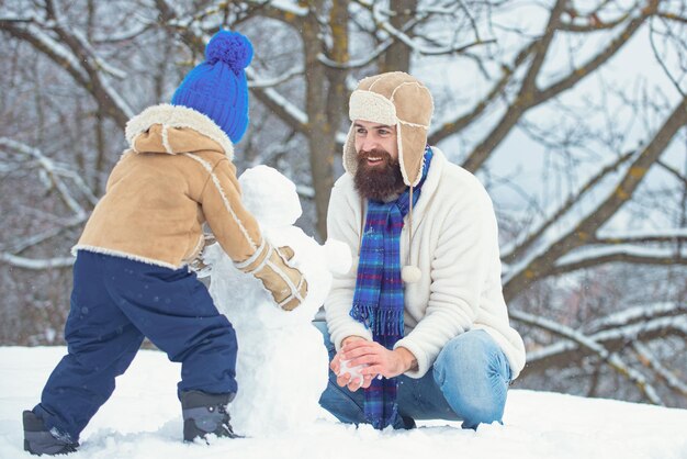 Wintervater und -sohn spielen im Freien frohe Weihnachten und ein glückliches neues Jahr