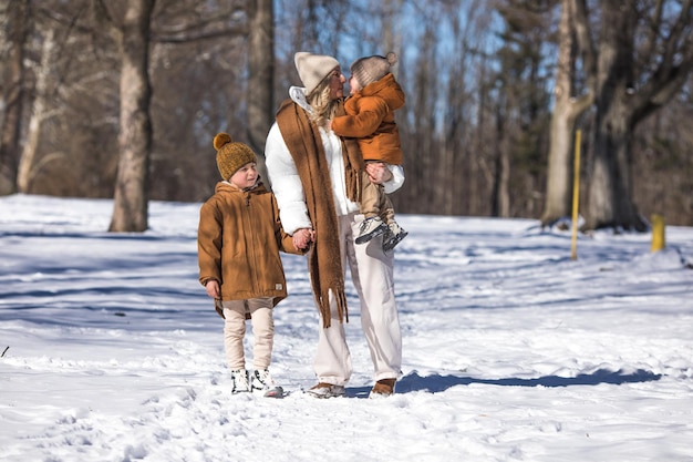 Winterwochenende Mutter und zwei Söhne in warmer Winterkleidung spazieren während sie sich im Winterwald unter Bäumen amüsieren