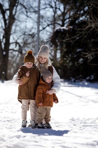 Winterwochenende Mutter und zwei Söhne in warmer Winterkleidung spazieren während sie sich im Winterwald unter Bäumen amüsieren