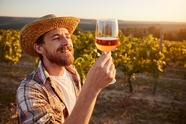 Winzer mit Glas Wein im Weinberg