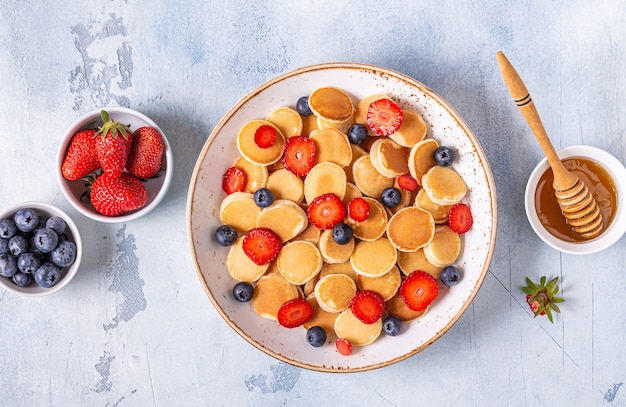 Winzige Pfannkuchen mit Erdbeeren und Blaubeeren zum Frühstück. Draufsicht.