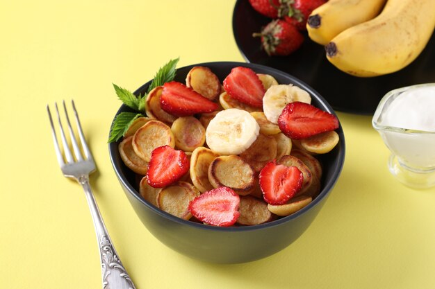 Winzige Pfannkuchen zum Frühstück mit Erdbeere, Banane und Sauerrahm