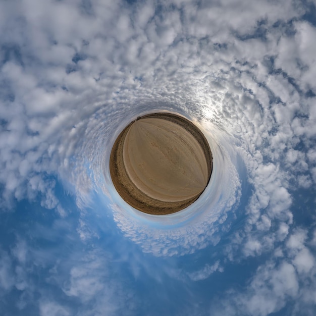 Winziger Planet im blauen bewölkten Himmel mit schönen Wolken mit Transformation des sphärischen Panoramas 360 Grad sphärische abstrakte Luftaufnahme Krümmung des Weltraums