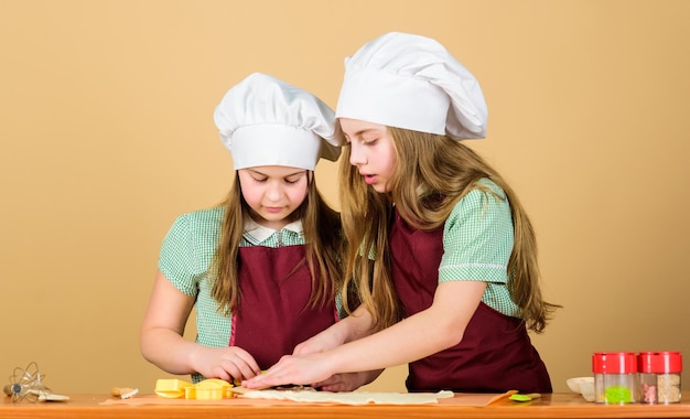 Wir kochen alles frisch aus unseren eigenen Öfen Entzückende Köchinnen Kleine Mädchen mit Kochmützen und Schürzen Kleine Köchinnen Rollpaste zum Plätzchenbacken