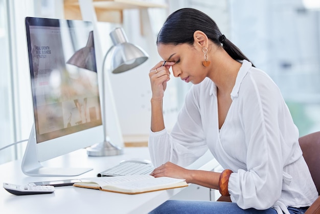 Wir leben unser Leben so, als würden all diese Dinge überleben Aufnahme einer jungen Geschäftsfrau, die in einem modernen Büro an einem Schreibtisch sitzt und überfordert wirkt