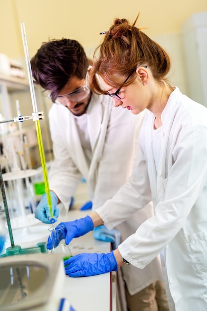 Foto wissenschaft, chemie, biologie, medizin und menschenkonzept. gruppe von medizinern, die im labor arbeiten