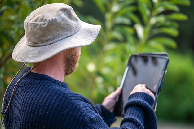 Foto wissenschaftler, agronom und landwirt, der im frühjahr bodenproben und gras auf einem feld untersucht und das pflanzenwachstum und die bodengesundheit mithilfe eines telefons und einer technologie untersucht, um zu sagen, dass er in australien verbunden ist