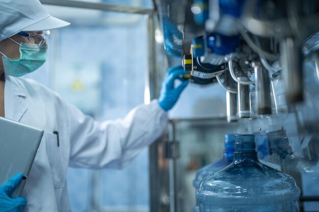 Foto wissenschaftler, der die qualität von wasserflaschen auf der maschinentransportlinie in einer fabrik überprüft