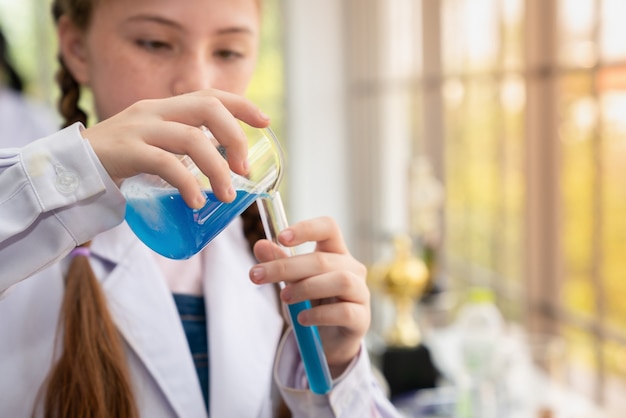 Wissenschaftler des jungen Mädchens, der Experimente chemisch im Glasrohr im Laborraum macht
