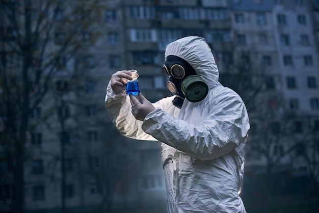 Wissenschaftler forschen im Freien mit weißem Overall und Gasmaske