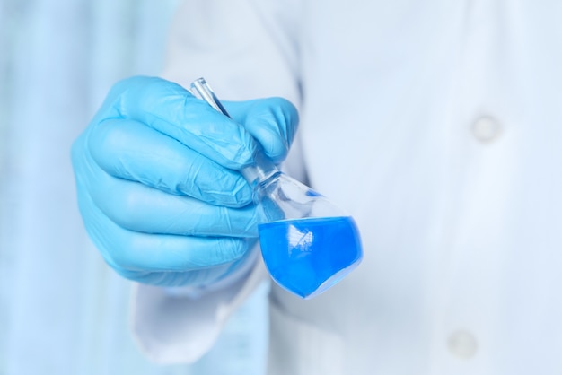 Wissenschaftler in blauen Handschuhen, der chemische Tests im modernen Labor durchführt