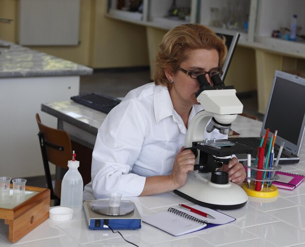 Foto wissenschaftler mit mikroskop auf dem tisch