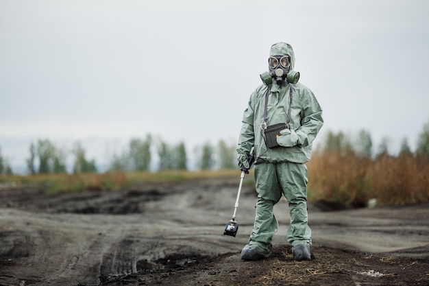 Wissenschaftler Strahlung Supervisor in Schutzkleidung und Gasmaske mit Geigerzähler überprüft die Höhe der radioaktiven Strahlung in der Gefahrenzone