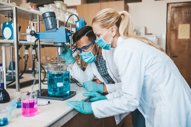 Wissenschaftler und Forscher mittleren Alters mit Gesichtsschutzmasken arbeiten im chemischen Labor an einem Coronavirus-Impfstoff.