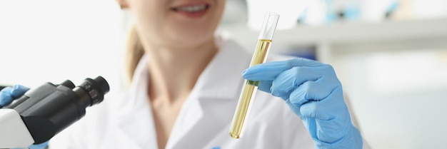 Wissenschaftlerin, die Assistent-Reagenzglas mit gelber Flüssigkeit im Labornahaufnahmelabor zeigt